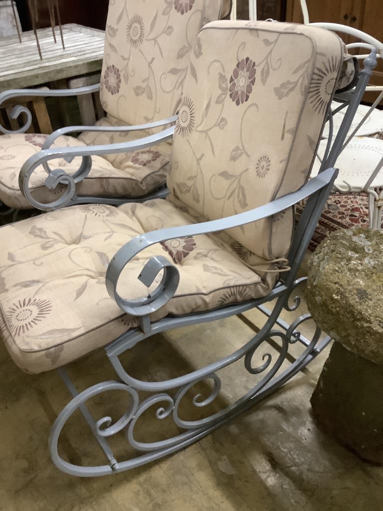 A pair of painted wrought iron garden rocking armchairs with cushion seats, width 57cm, depth 86cm, height 93cm